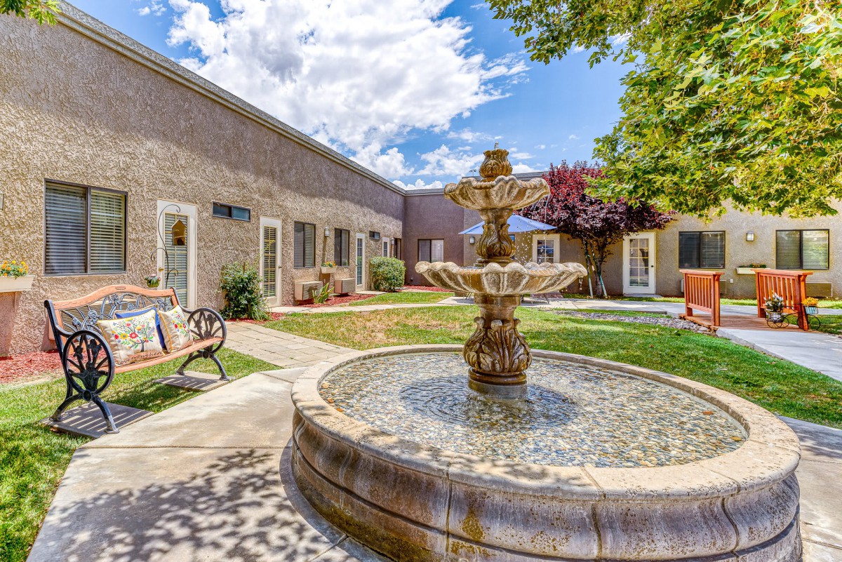 A serene courtyard with a central fountain surrounded by a well-maintained garden and seating areas.