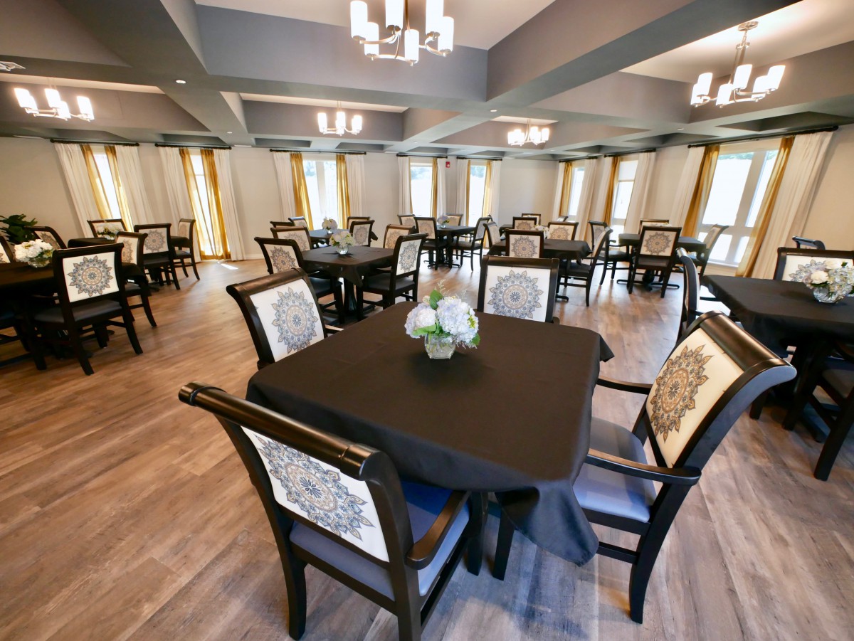A spacious dining room with elegantly set tables and comfortable chairs.