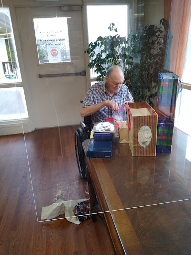 A senior man engaged in an activity at a table in a care facility.