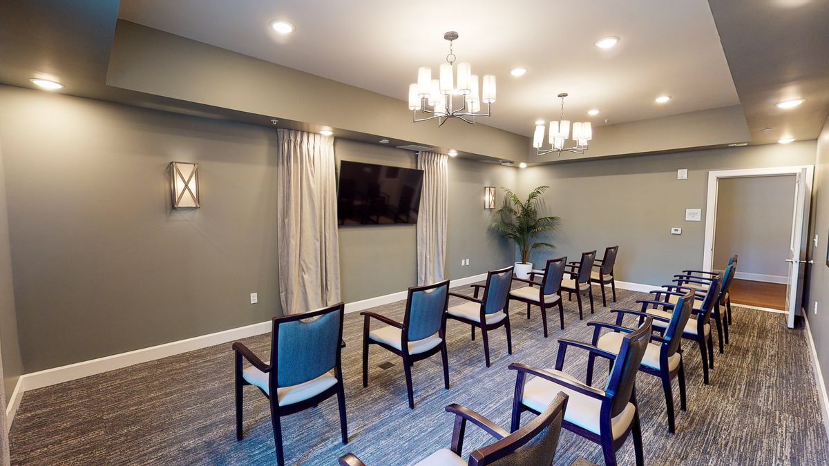 A modern conference room setup with chairs facing a television, well-lit with decorative lighting.