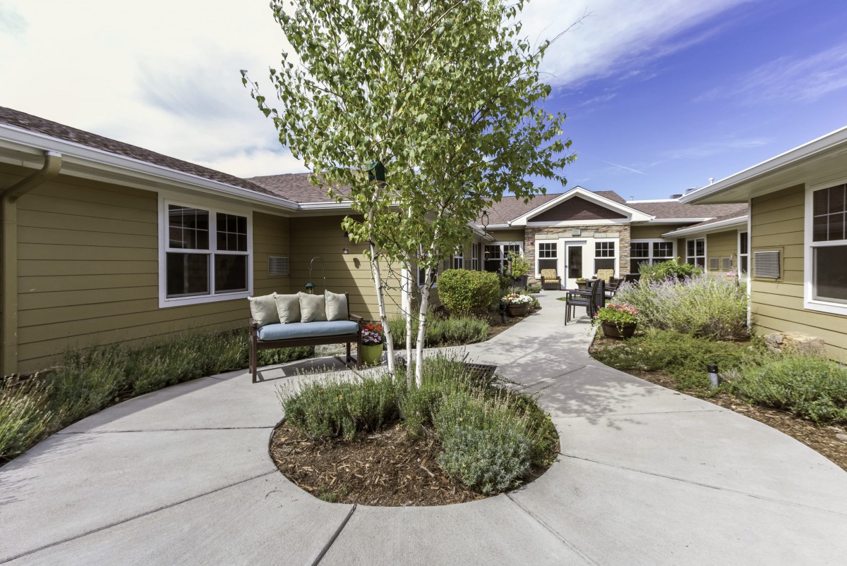 A beautifully landscaped courtyard with a central tree and outdoor seating area.