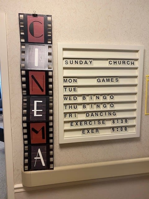 Weekly activity schedule with a cinema-themed design, featuring events like church, crafts, bingo, and exercise classes.
