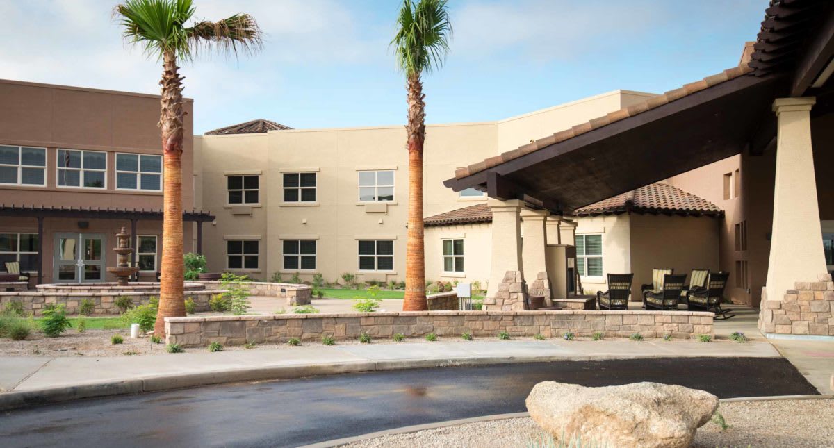 A modern building with a landscaped entrance and palm trees.