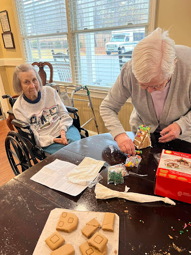 Two elderly residents engage in a crafting activity at a care facility.