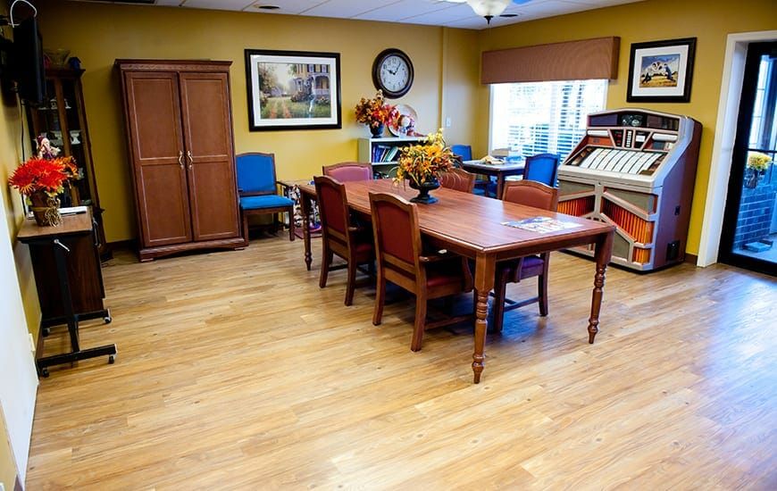 A cozy dining room with a wooden table and chairs, featuring colorful decor and a large cabinet.