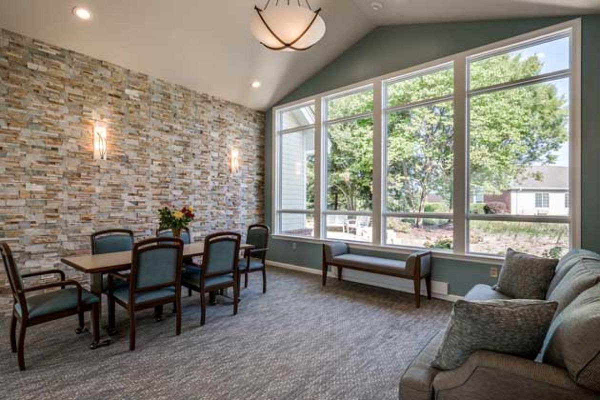 A cozy dining area with large windows and a stone accent wall, allowing natural light to fill the space.