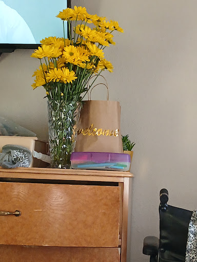 A cheerful display of yellow flowers alongside wrapped gifts on a wooden surface.