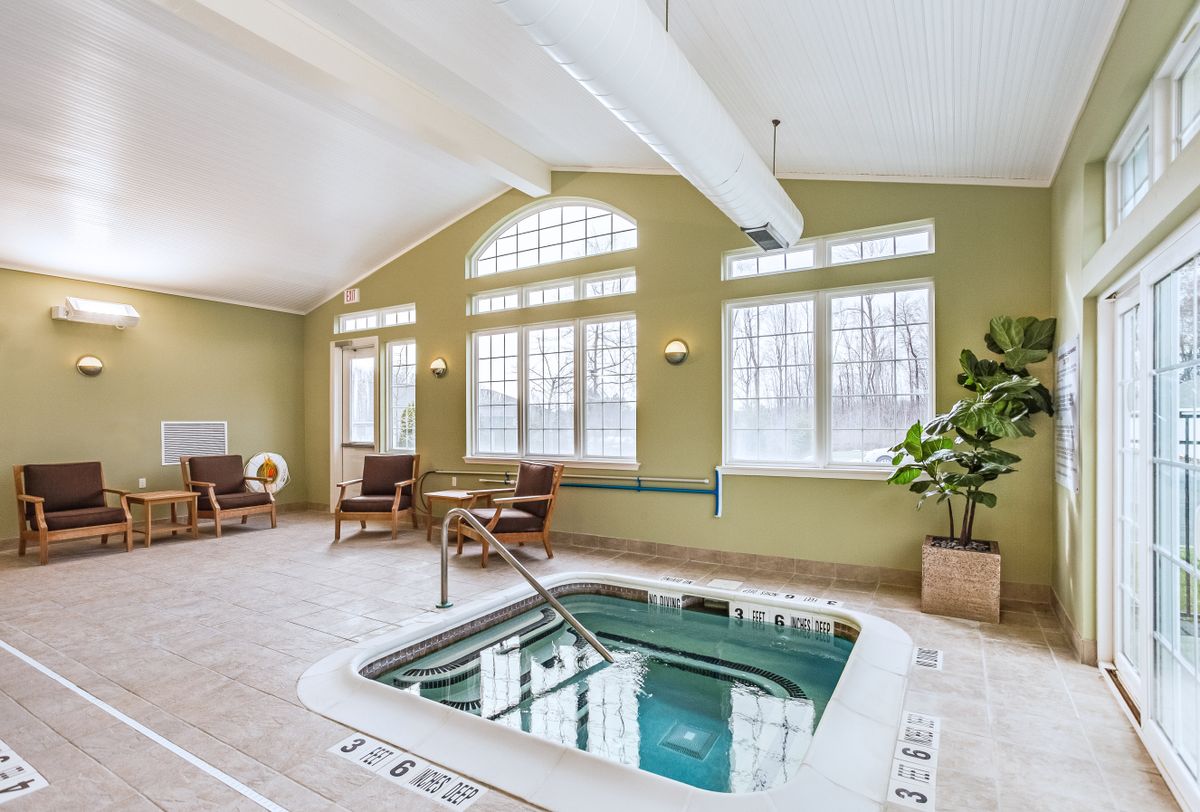 A cozy indoor spa facility with a jacuzzi and comfortable seating, illuminated by natural light from large windows.