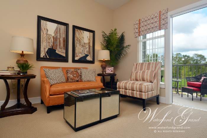 A cozy living room with a stylish orange sofa, striped armchair, and modern coffee table, complemented by artwork on the wall and natural light from the window.
