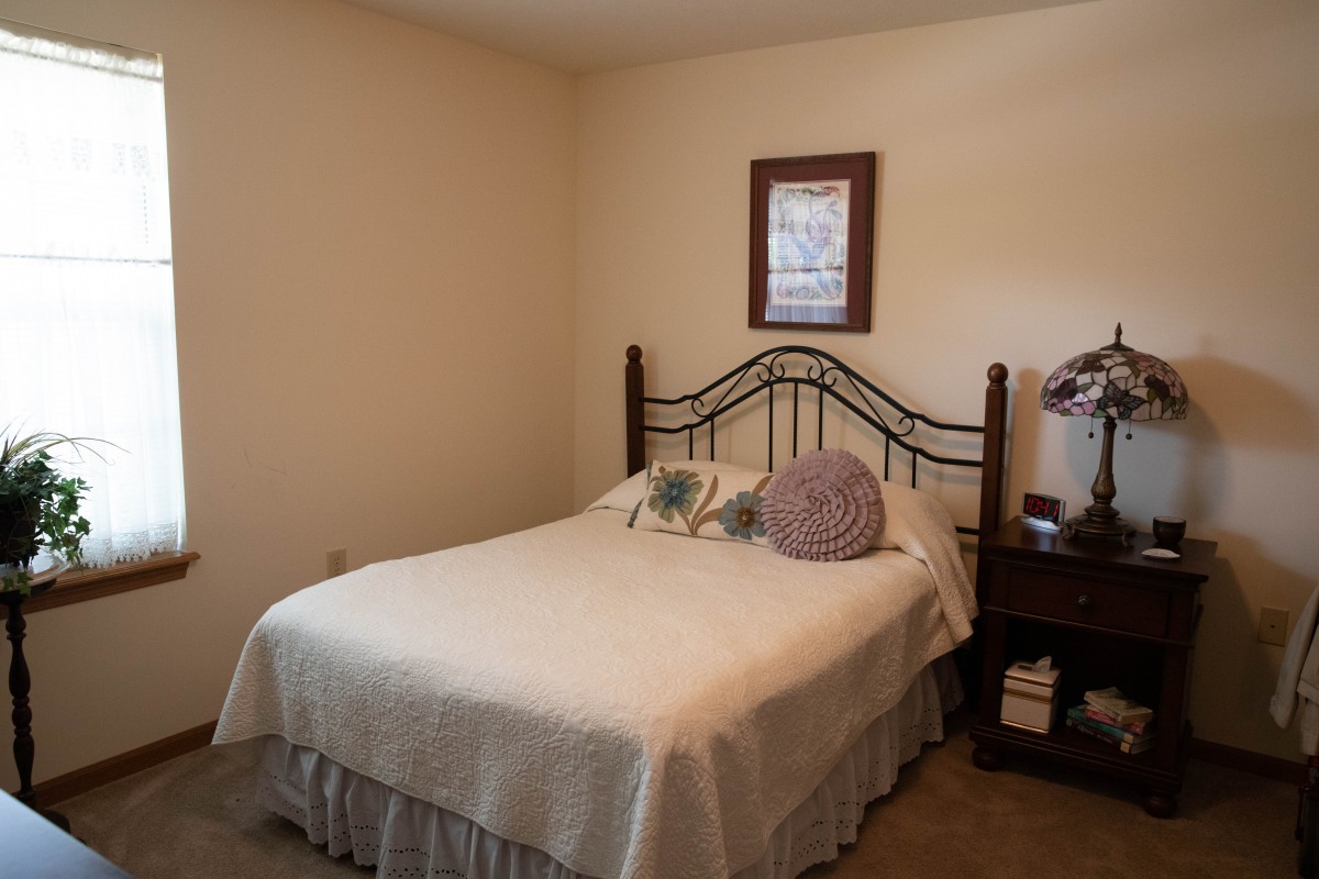 A cozy bedroom with a neatly made bed, nightstand, and framed picture on the wall.
