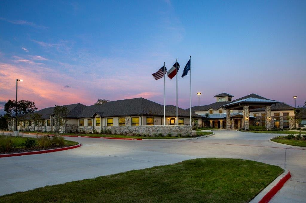 A building with flags at dusk under a colorful sky.