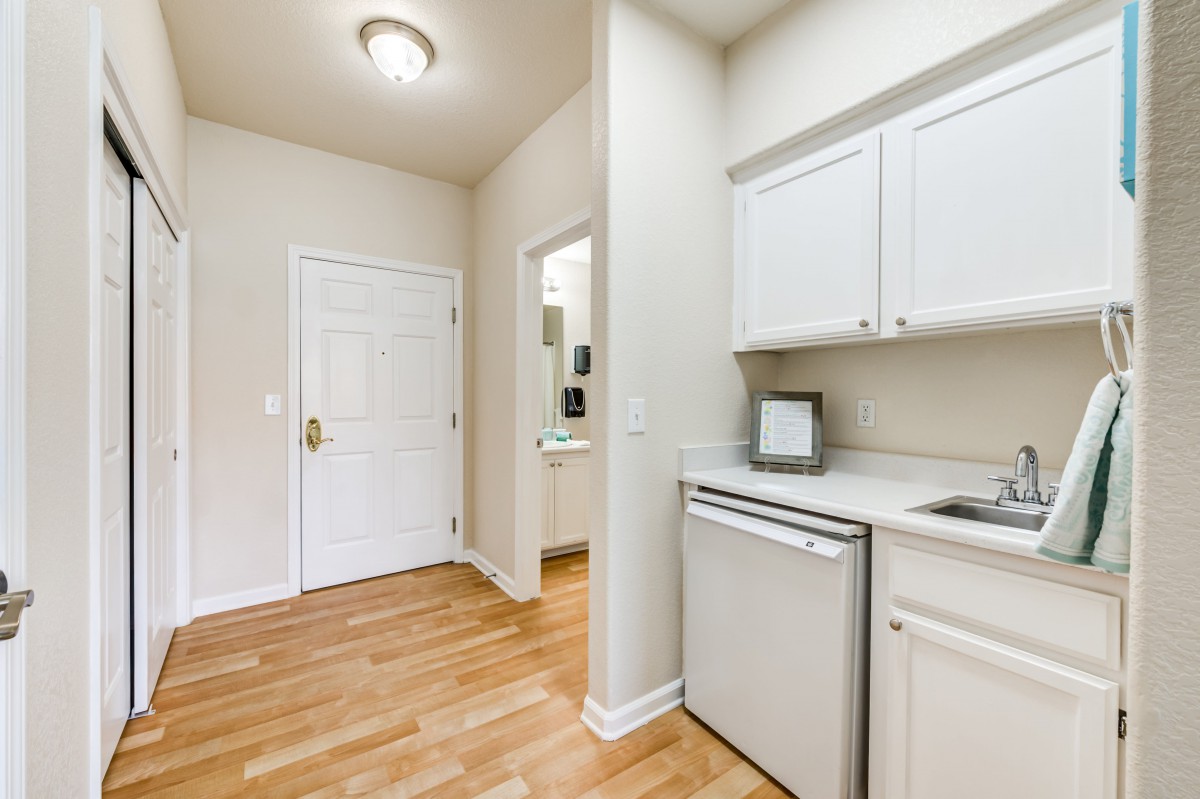 A compact kitchen area with white cabinets and hardwood flooring in an apartment.