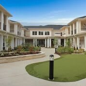A modern residential building with a central courtyard and landscaped gardens.