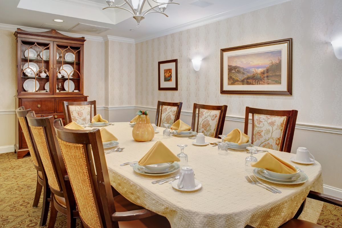 A well-decorated dining room with a long table set for a formal meal.