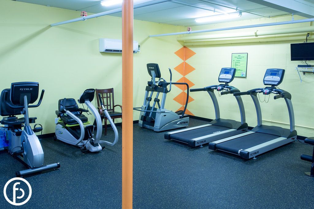 A small gym room equipped with treadmills, a stationary bike, and an elliptical machine.