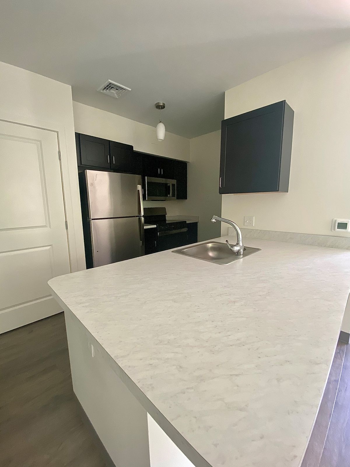 A modern apartment kitchen with stainless steel appliances and a large countertop.