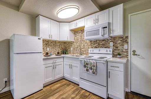 A modern kitchen featuring sleek white cabinetry and stylish stone backsplash.