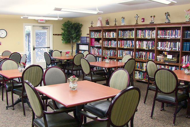 A cozy library reading area with shelves full of books and several tables and chairs for visitors.