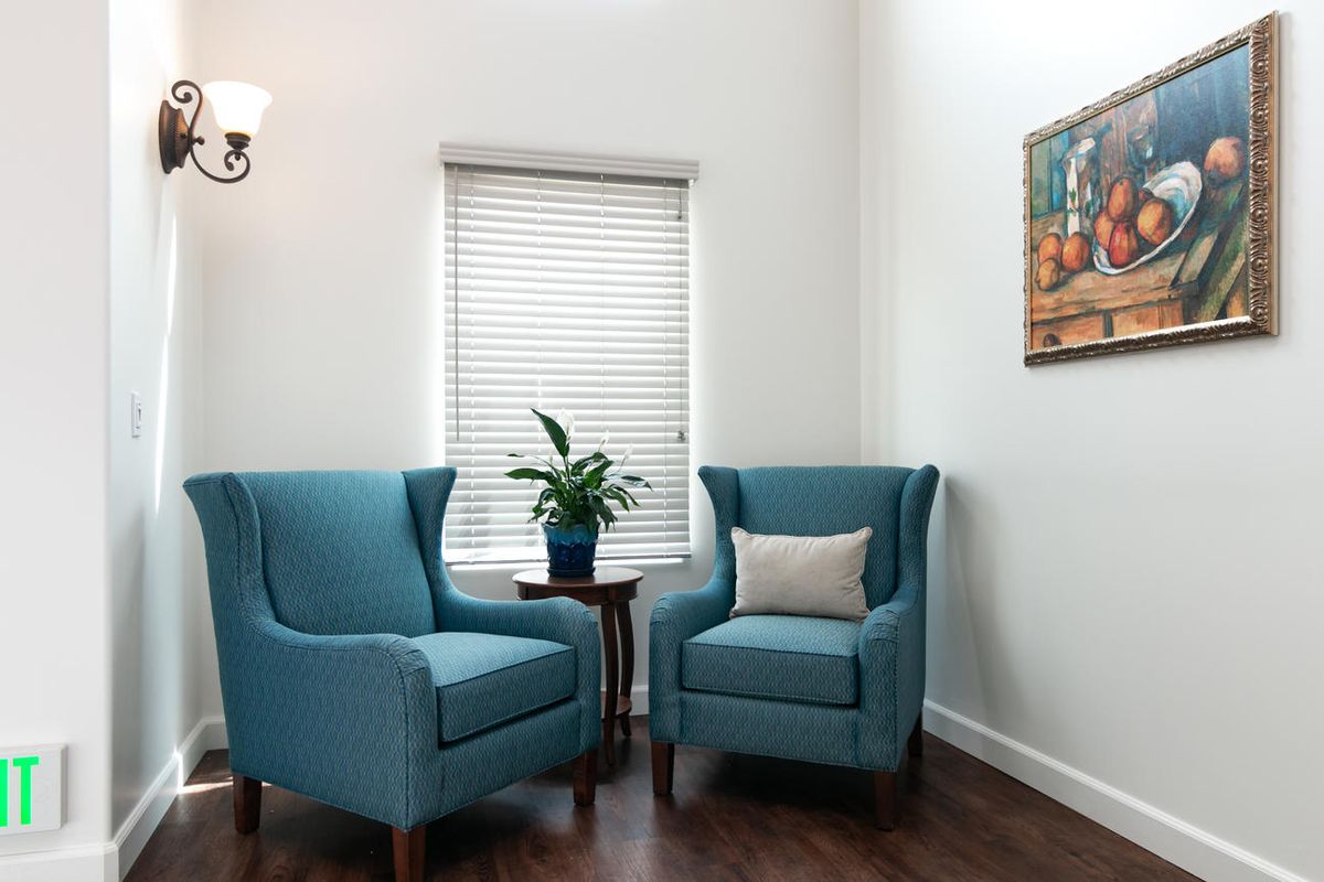 A cozy living space featuring two teal armchairs and a small table with a potted plant.