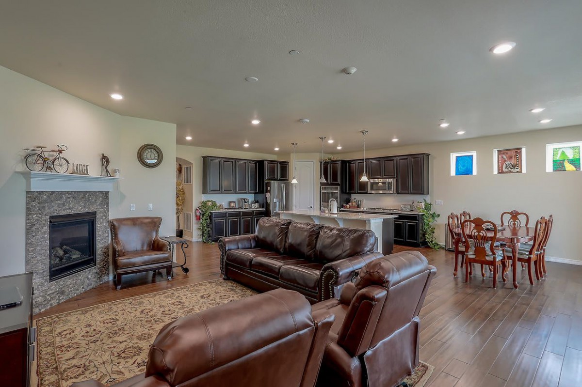 A spacious open-concept living area featuring a modern kitchen, comfortable leather seating, and a dining space on hardwood floors.