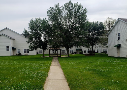 A peaceful view of an apartment complex surrounded by greenery and a walking path.