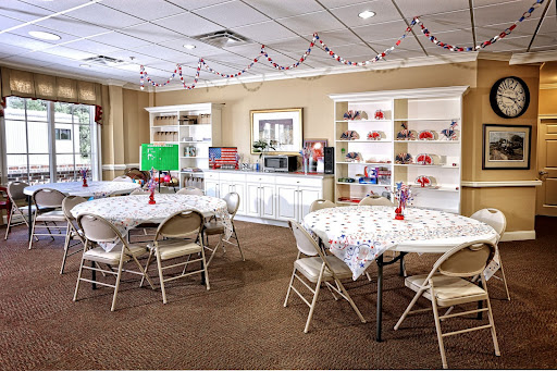 A welcoming community room equipped with tables, chairs, and shelves, perfect for gatherings and events.