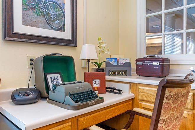 A vintage office setup with a typewriter on the desk, surrounded by various decorative items and furniture.