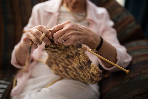 An elderly person skillfully knitting a piece of yarn, showcasing the art of crafting.