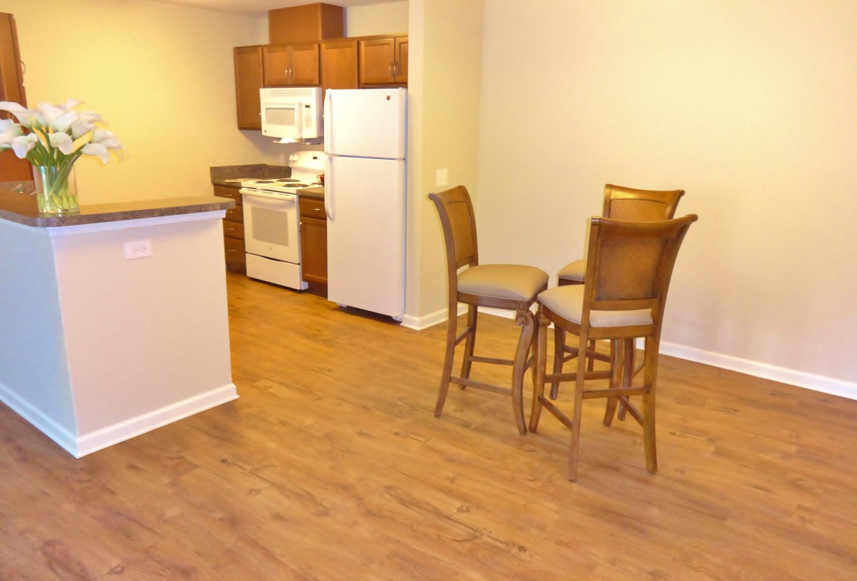 A cozy apartment kitchen and dining area with wooden flooring and simple furniture.