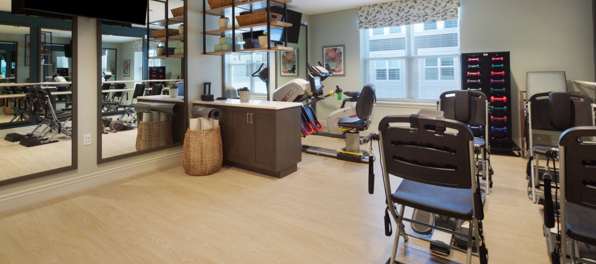 A home exercise room with various fitness equipment and a large window.
