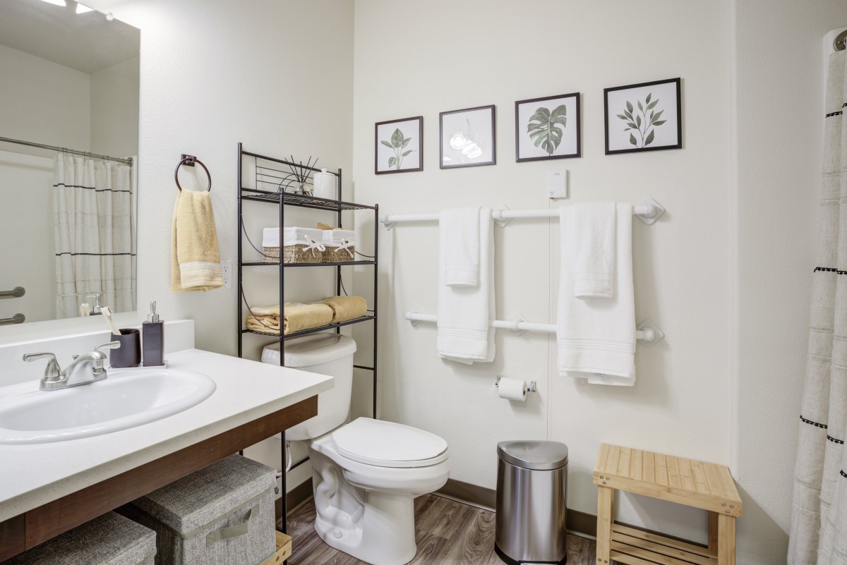 A modern bathroom with organized shelving, wall art, and neatly arranged towels.