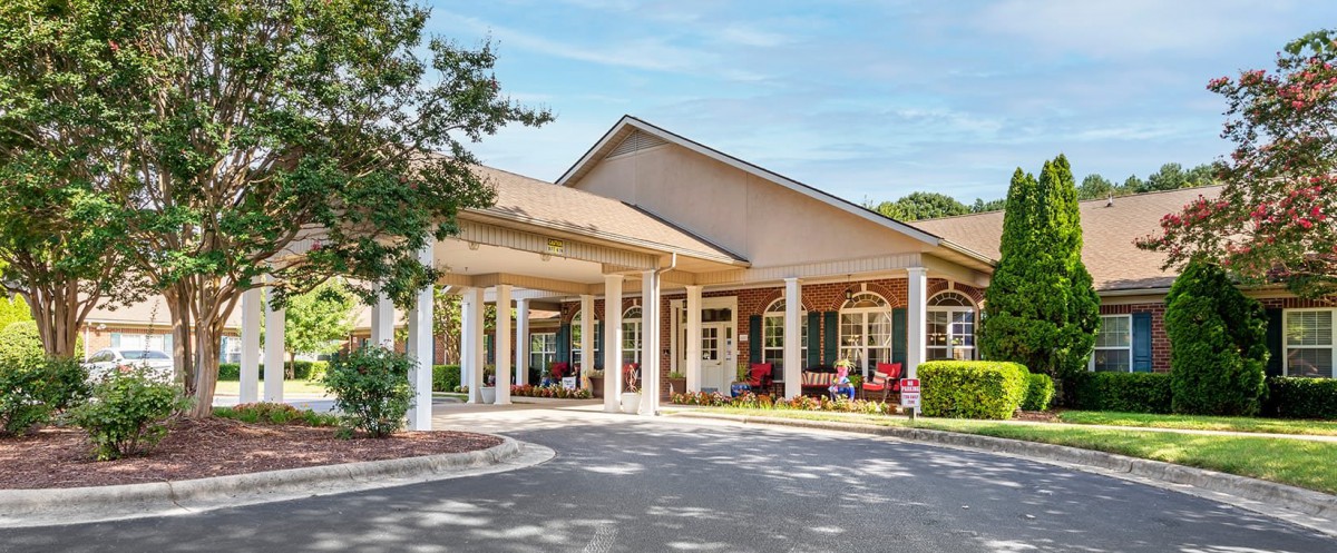 A welcoming entrance to a residential building with white columns and outdoor seating.
