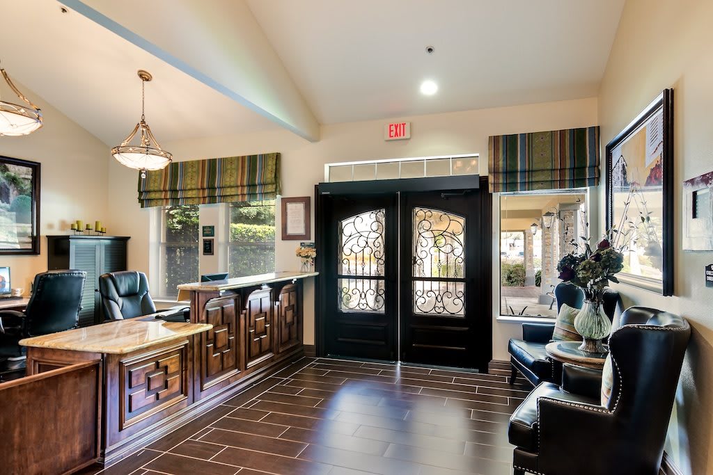 A well-furnished lobby featuring a reception desk, a seating area, and ornate double doors.