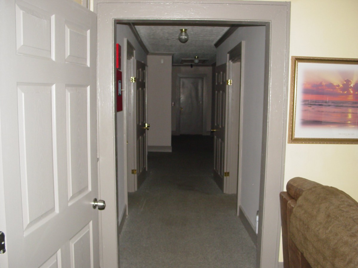 A view of a narrow hallway with doors on both sides.