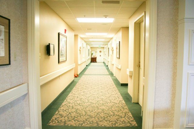 A well-lit hallway with carpeted flooring and multiple doors on either side.