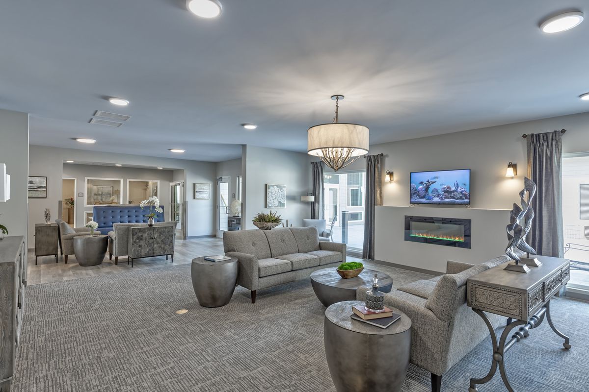 A modern living room with stylish furniture, a chandelier, and a fireplace.