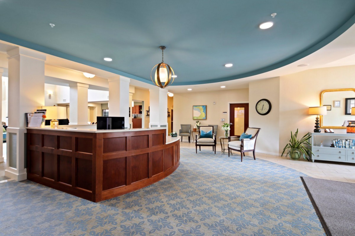 A modern office lobby featuring a wooden reception desk and a seating area with contemporary decor.