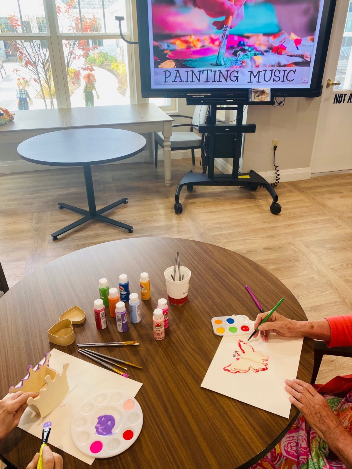 Senior residents engaging in a painting activity with music accompaniment.