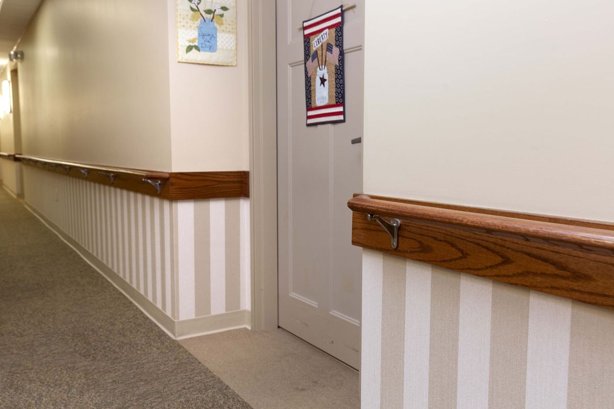 A hallway with striped walls, featuring a door adorned with artwork and wooden handrails.
