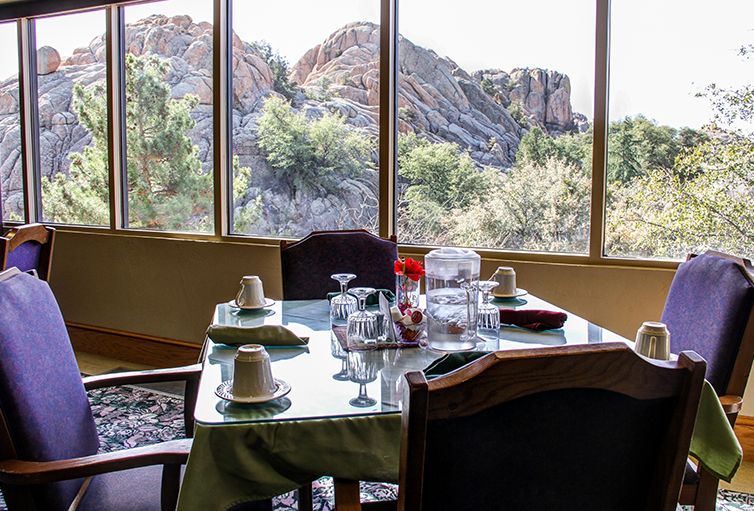 A dining table set near large windows with a scenic mountain view.