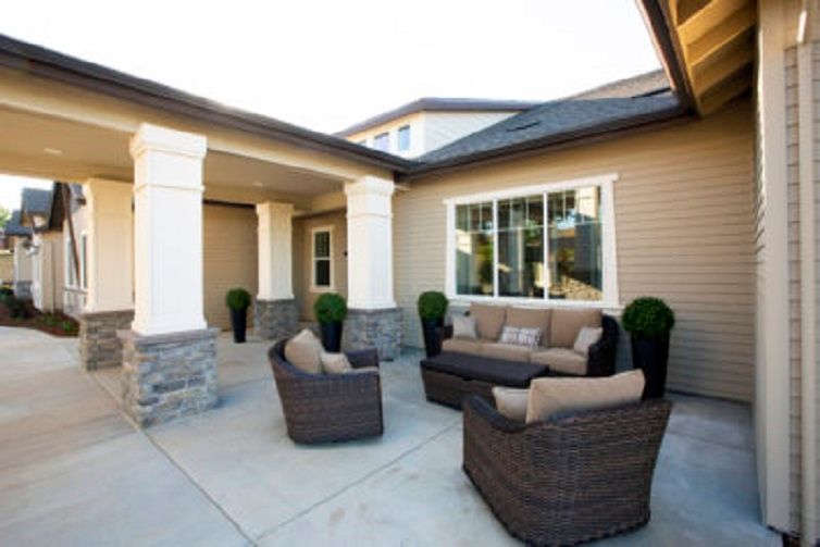 A cozy outdoor seating area on a house porch with wicker furniture and cushions.