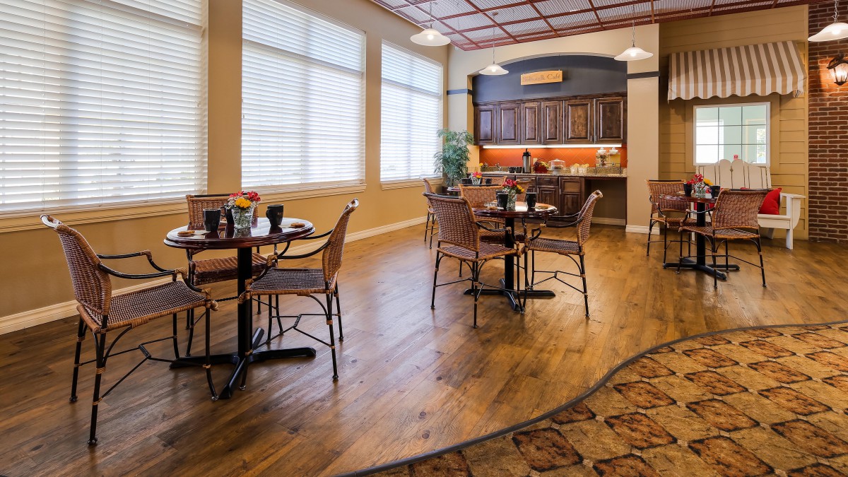 A cozy dining area with wooden floors, tables, and chairs arranged in a well-lit space.