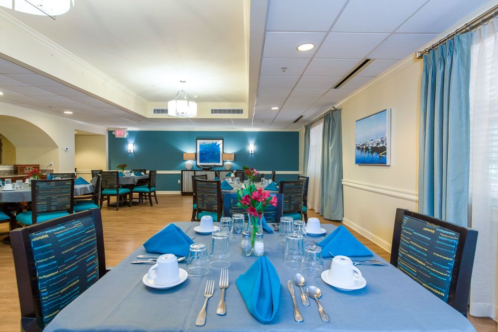An elegantly set dining table with blue napkins and floral centerpiece in a well-lit dining room.