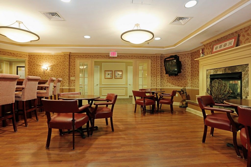 A well-lit dining area with wooden tables and chairs, featuring elegant decor and a mounted television.