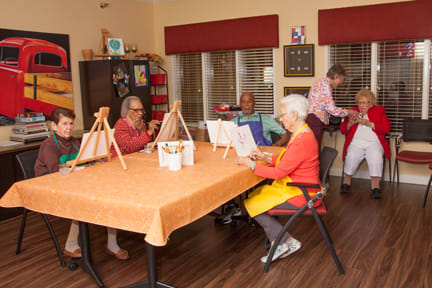 A group of seniors engaged in a painting class, enjoying creative time together indoors.