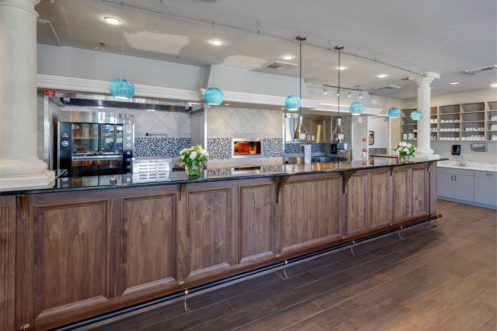A modern kitchen with wooden cabinetry and a sleek bar counter, featuring hanging pendant lights.