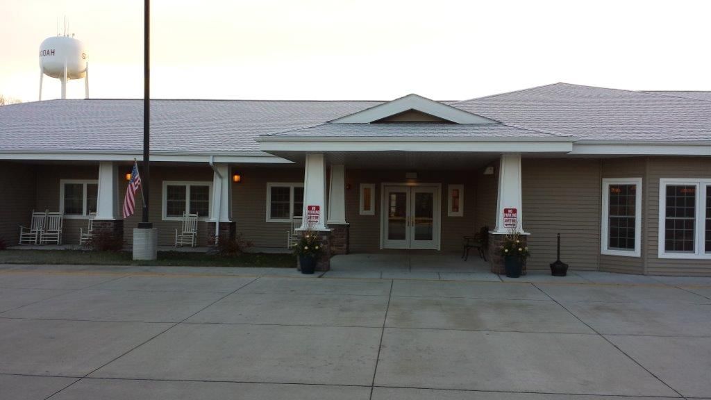 Front view of a building entrance with columns and decorative plants.