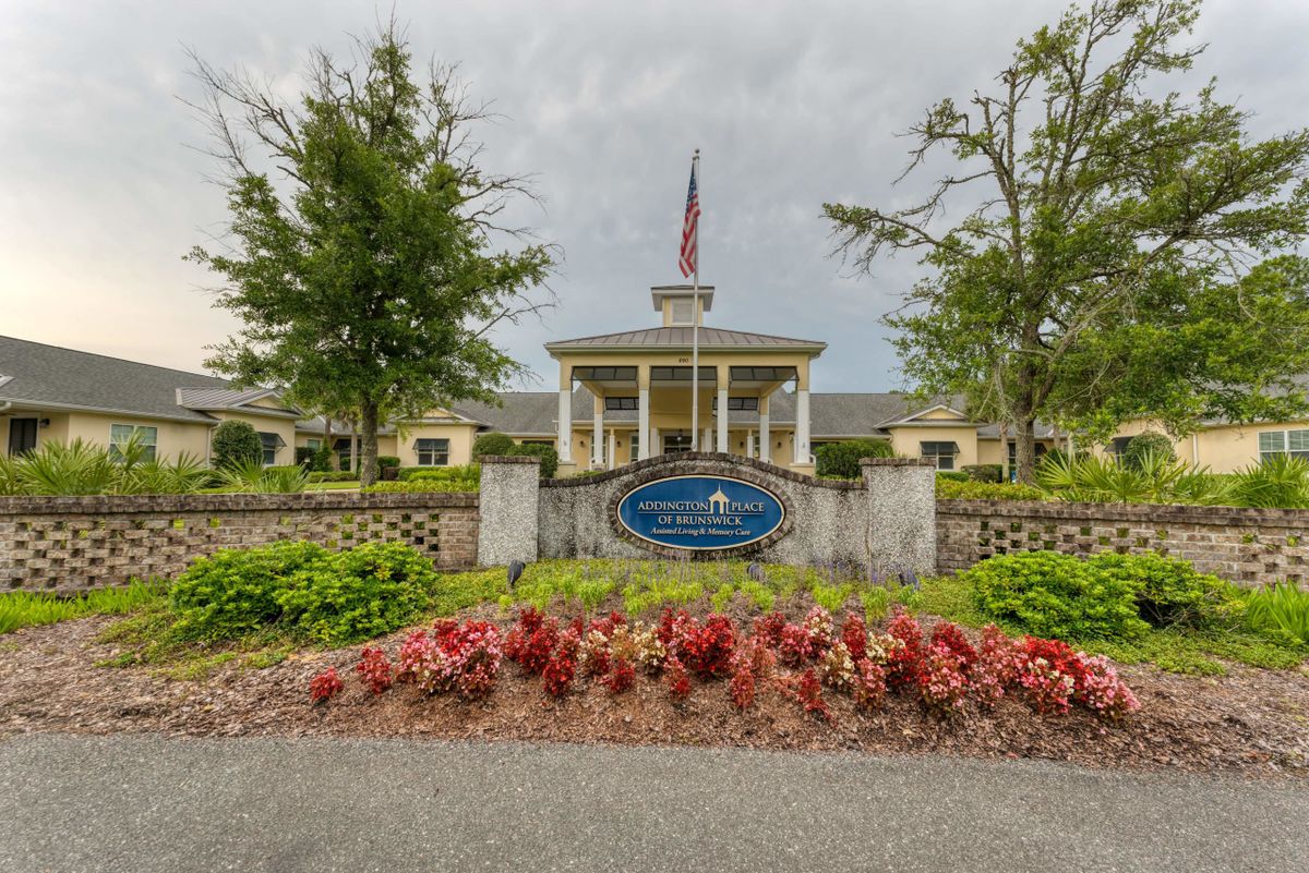Entrance to a facility with a manicured garden and American flag.