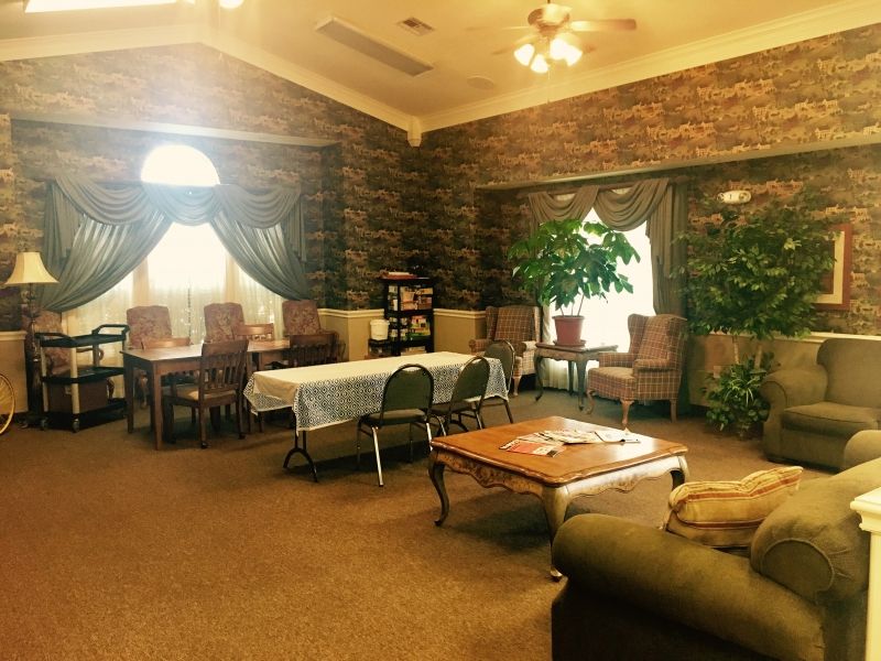 A cozy living room with comfortable seating, decorated with plants and natural light from large windows.