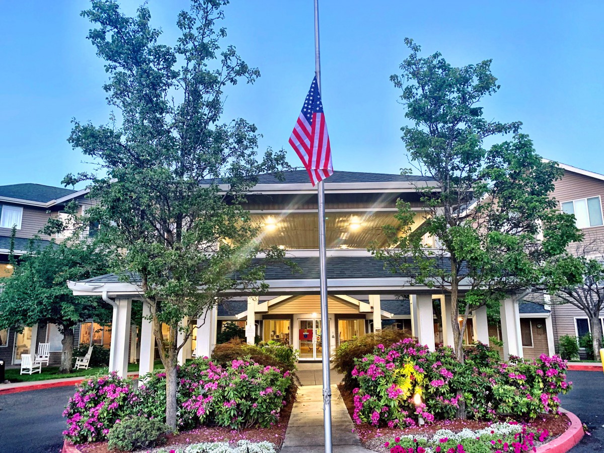 A beautifully landscaped building entrance with a prominently displayed American flag.